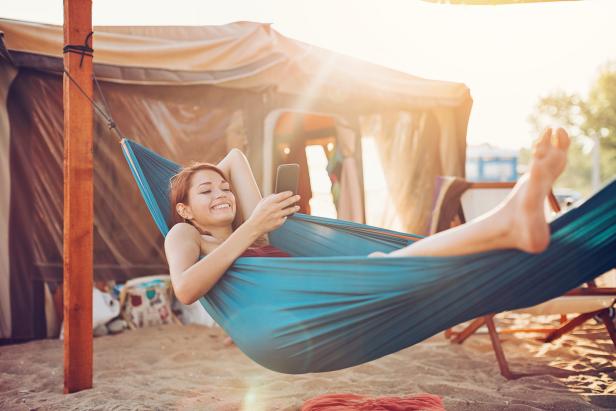 Young woman with smart phone resting in a hammock