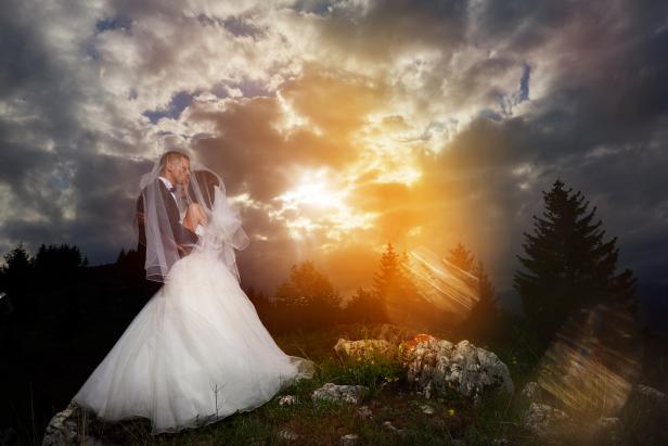 romantic moment between bride and groom, embracing at sunset and loving. dramatic sunset sky.