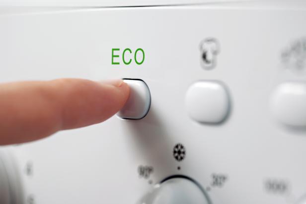 Finger pressing ECO button on washing machine.Other images in this series: