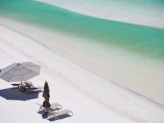 Above view of beach beds and umbrellas at tropical coast