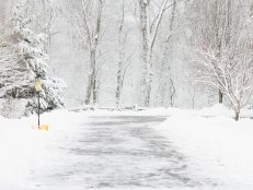 Yellow snow shovel, placed along the side of a driveway, that has been freshly shoveled. Taken in winter.