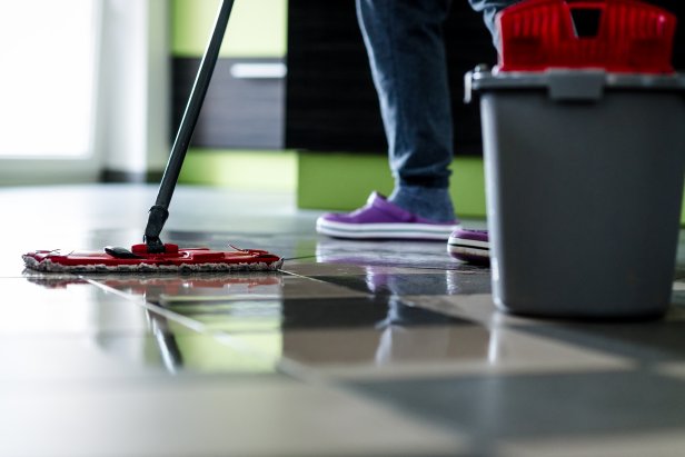 Cleaning with mop. Ceramic floor tiles are wet.