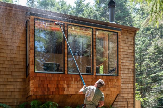 Man washing window with long pole and brush outdoors in California