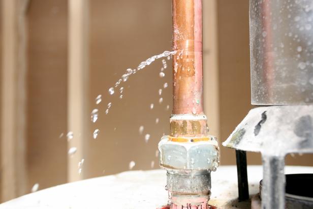 Water leaking out of a pipe on top of a water heater.