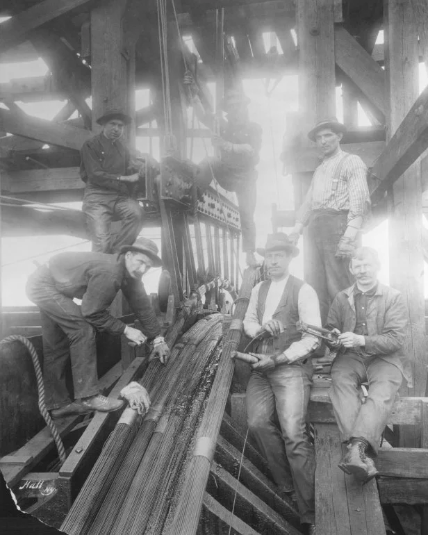 Workmen cutting and tying tension cables.