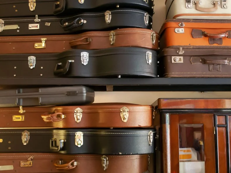 Guitar cases, vintage suitcases, wooden cabinet with glass doors