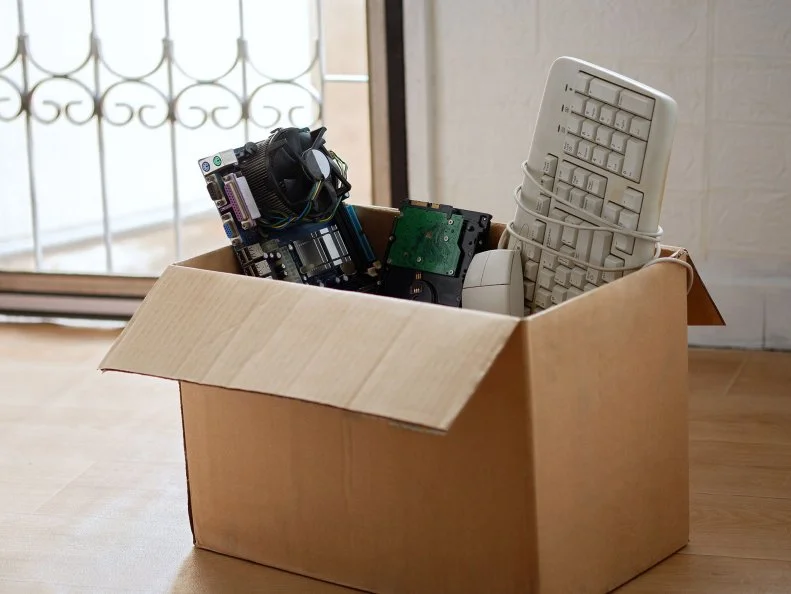 Old hard disk dive and motherboards and used keyboard with mouse old computer hardware accessories in paper boxes, Obsolete equipment is electronic waste Reuse and Recycle concept.