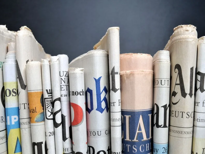News - Folded newspapers in front of black wall