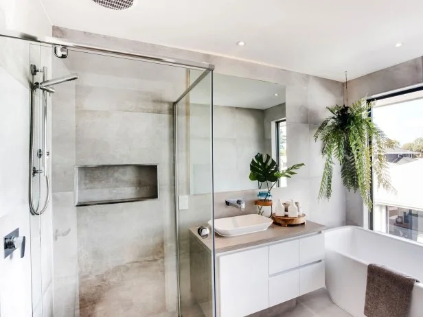 A bathroom with a glass walled shower and plants.