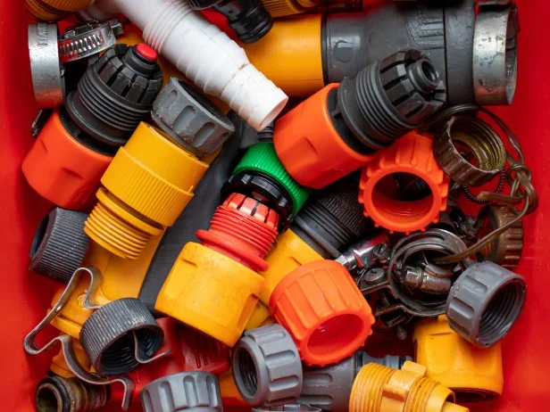 Assorted colorful garden hose connectors and irrigation fittings in container