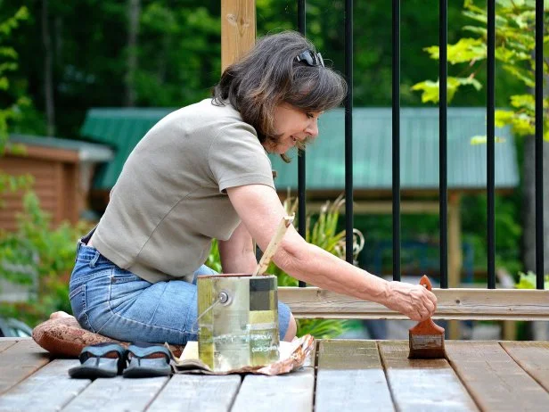 woman applying top coat to a deck
