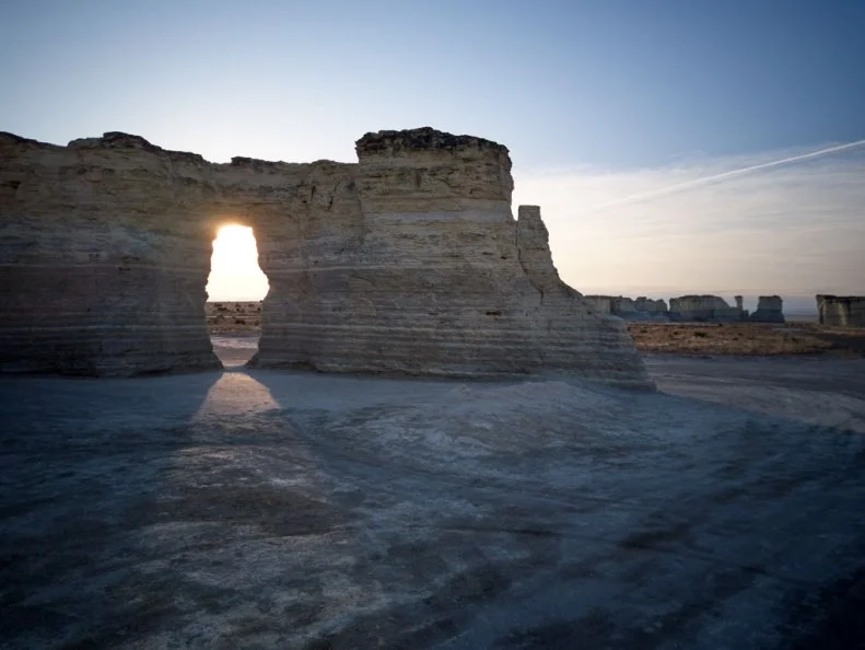 Sunset at Monument Rocks chalk Pyramids, Kansas with a beam of light shining through a natural eroded arch in the rock formation