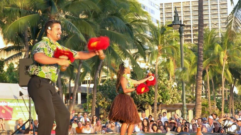 HONOLULU, UNITED STATES OF AMERICA - AUGUST 6 2015: a male and female hula dancer with uliuli perform at waikiki beach