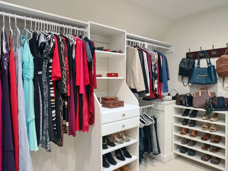 A large walk-in closet with color-coded clothing racks, shoe shelves, and hanging handbags.