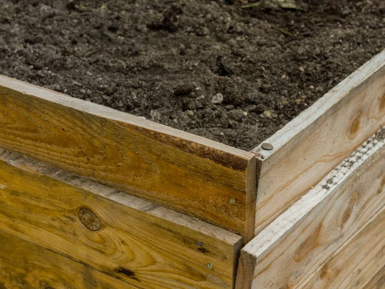 Upclose view of a corner on a wood frame raised garden bed.
