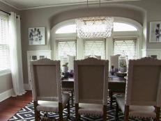 The dining room redesign is complete with a glass chandeilier, dining chaird, printed rug and custom artwork.